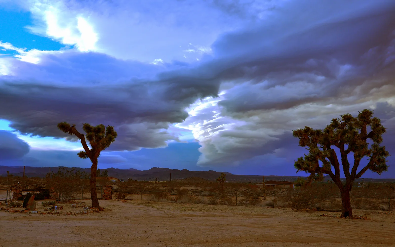 Massive clouds sweeping across the open Mojave Desert landscape under a blue sky